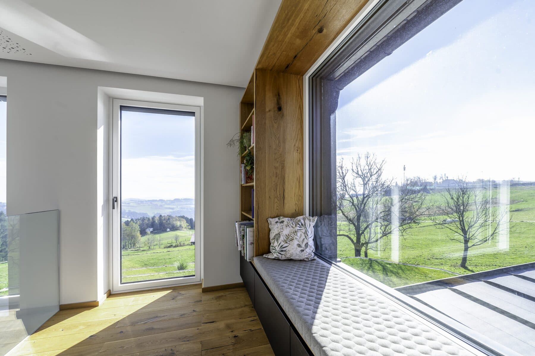 Fenêtre bois/aluminium Internorm avec banquette et vue sur la campagne, photo Internorm