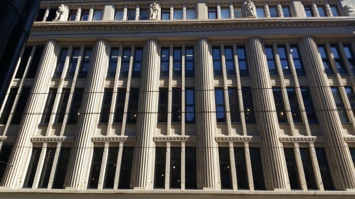 Façade en pierre du bâtiment Globus à Genève avec fenêtres bois/aluminium